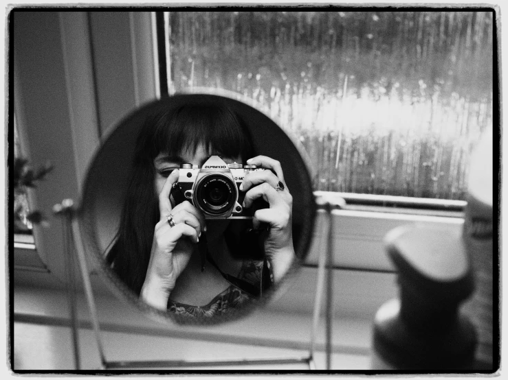 a woman taking a picture of herself in a mirror, a black and white photo, inspired by Henri Cartier-Bresson, flickr contest winner, purism, with a fringe, taken on a 1960s kodak camera, taken on a ww2 camera, amanda lilleston