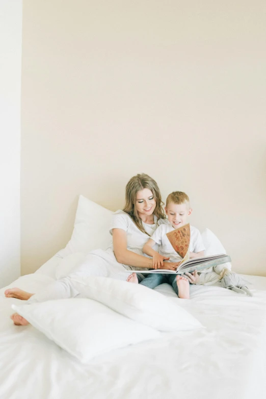 a woman reading a book to a child on a bed, by Nicolette Macnamara, pexels, plain background, white bed, posed, avatar image