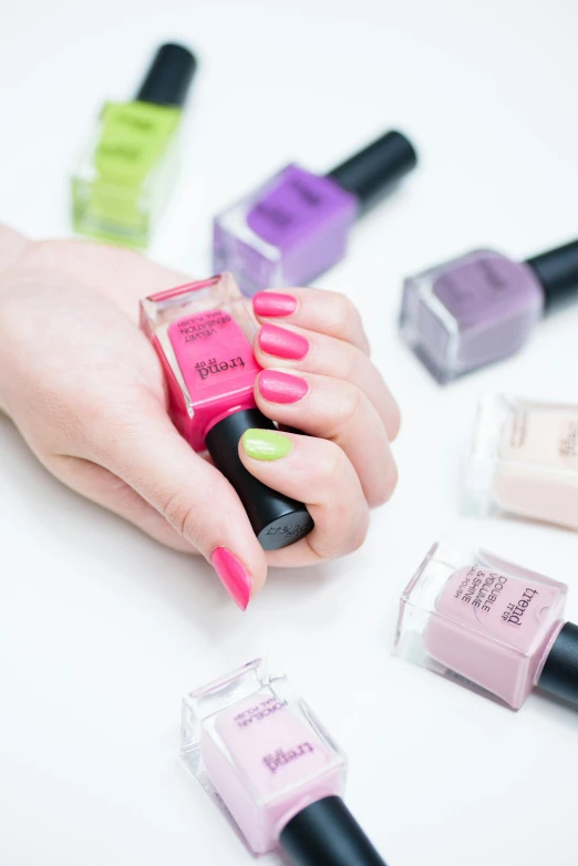 a close up of a person holding a bottle of nail polish, inspired by Maud Naftel, color field, lime and violet, pinks, detailed product image, fierce