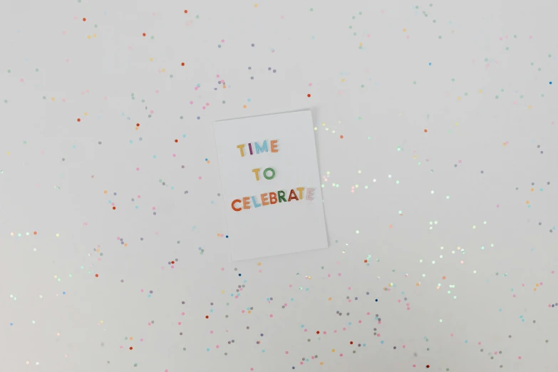 a cake sitting on top of a table covered in confetti, by Nicolette Macnamara, temporary art, typography, minimalist sticker, time, celebrate goal