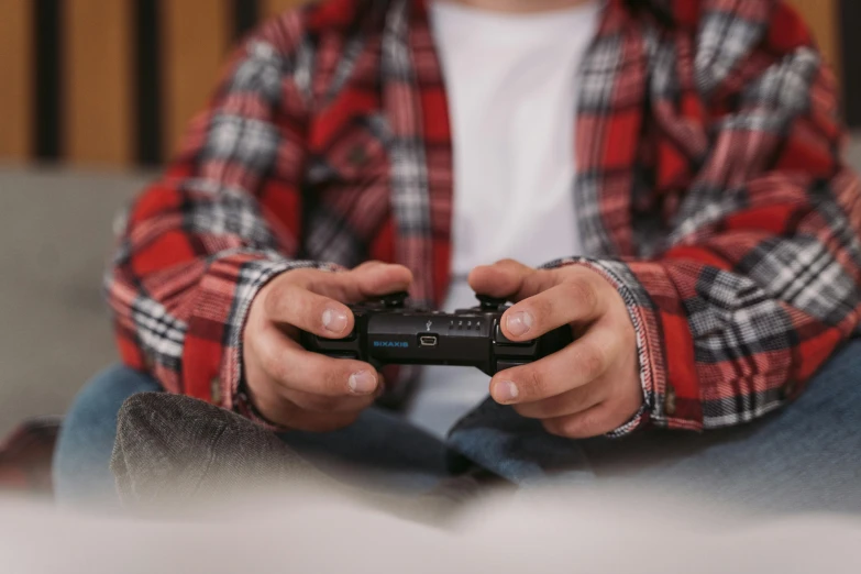 a person sitting on a couch holding a video game controller, pexels, wearing a red lumberjack shirt, avatar image, children's, performing