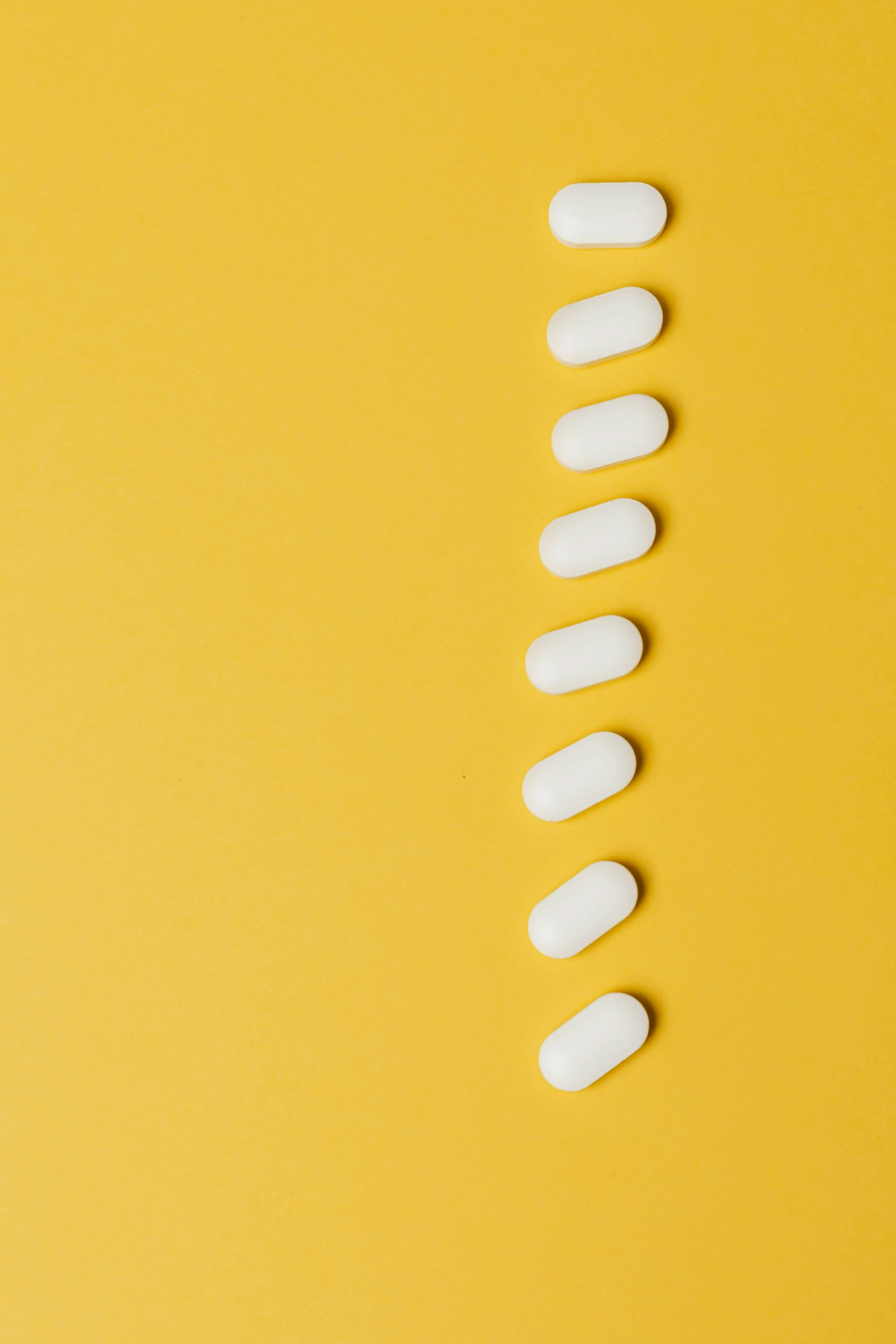 a row of white pills on a yellow background, by Sebastian Vrancx, trending on pexels, antipodeans, 9 peacock tails, arcs, minimalist photorealist, 1x