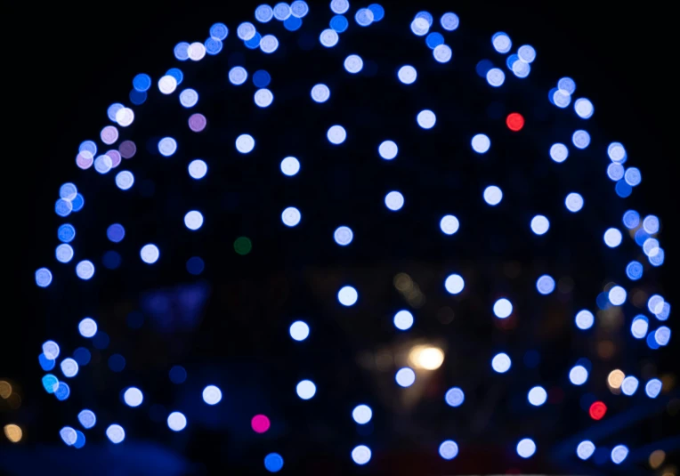 a close up of a cell phone in front of a christmas tree, by Niko Henrichon, pexels, visual art, blue headlights, dots abstract, glowing sphere, white lights