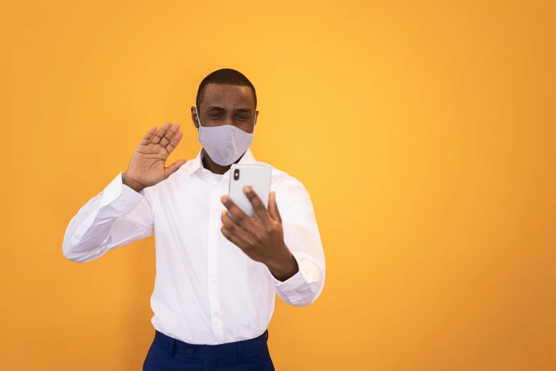 a man in a white shirt and tie making a stop sign with his hands, by Carey Morris, pexels contest winner, surgical mask covering mouth, in front of an orange background, smartphone photo, african man