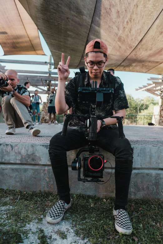 a man that is sitting down with a camera, posing for a picture