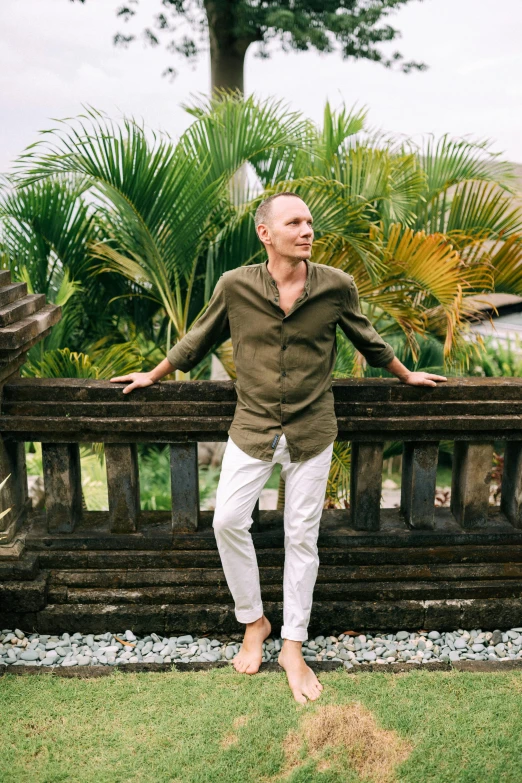 a man standing on top of a wooden fence, a portrait, inspired by Pete Morhbacher, unsplash, renaissance, no hair completely bald, tropical style, full - length photo, photo of putin