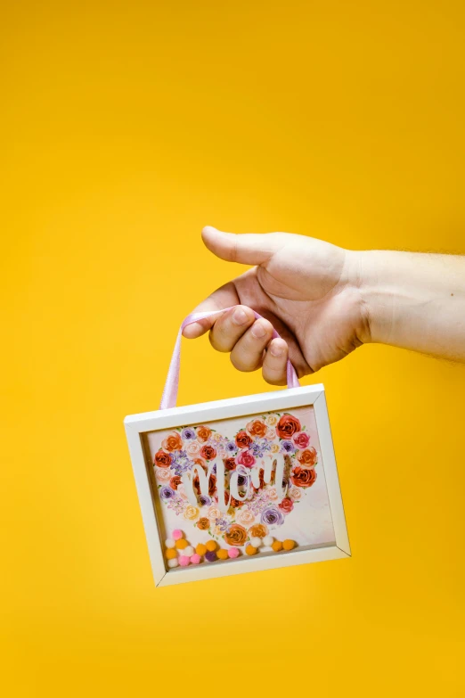 a person holding a box with flowers on it, light frame, multicoloured, motherly, love craft