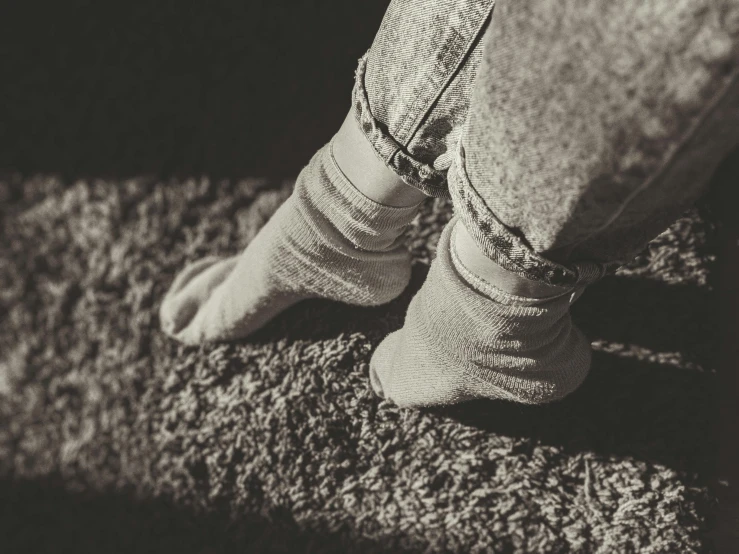 a black and white photo of a person's feet, a black and white photo, inspired by Elsa Bleda, photorealism, everything is carpet and 3d, young child, wearing jeans, sepia colors