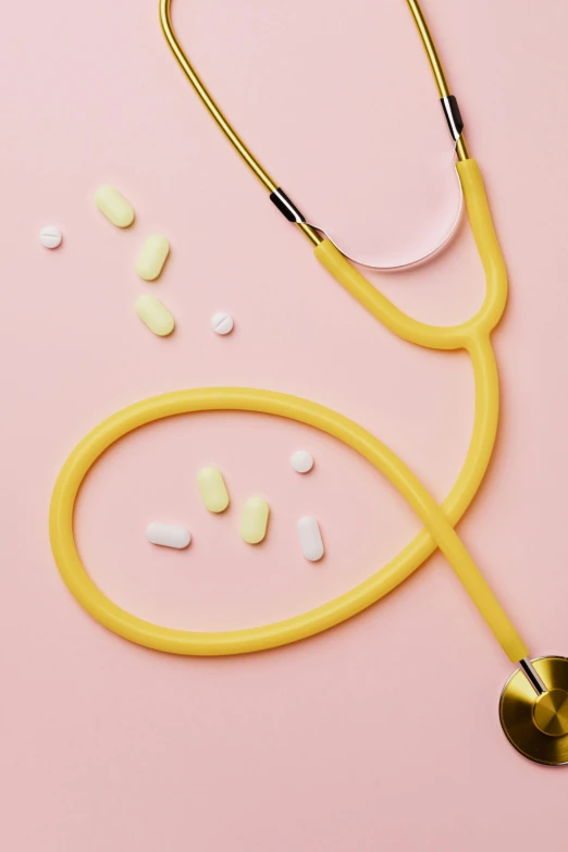 a stethoscope and pills on a pink background, by Rachel Reckitt, colors: yellow, candy worms, hero shot, multiple lights