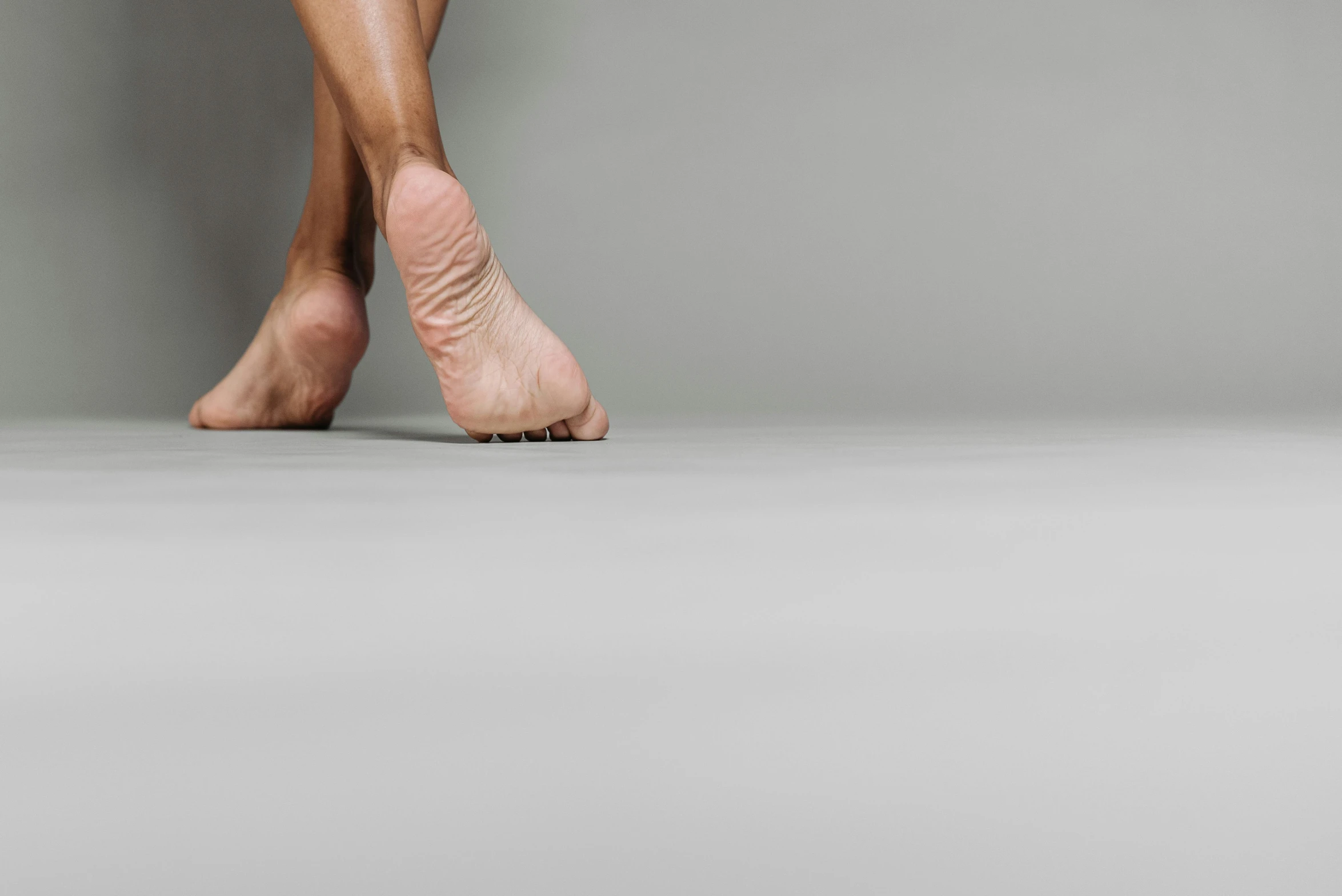 a close up of a person's bare feet, trending on pexels, hyperrealism, on grey background, dance, 15081959 21121991 01012000 4k