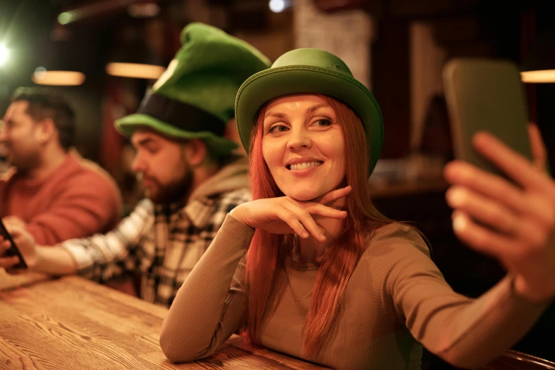 a group of people sitting at a table with cell phones, wearing green tophat, irish, amouranth, portrait image