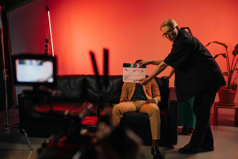 a man sitting on top of a couch next to a woman, pexels contest winner, red camera, behind the scenes, photoshoot for skincare brand, felix englund style