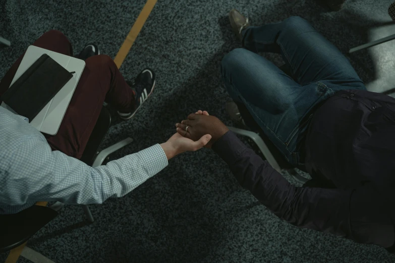 a group of people sitting around each other holding hands, by Carey Morris, pexels contest winner, hurufiyya, tv still frame, medium shot of two characters, holding each other, promotional image