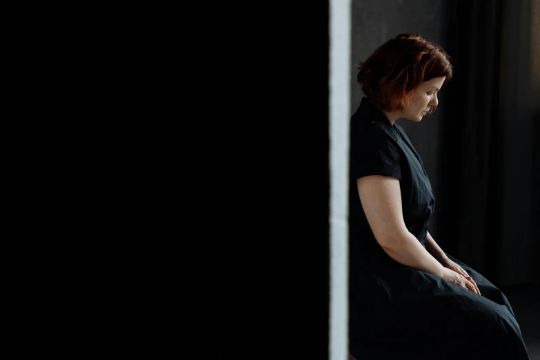 a woman sitting on a chair looking out a window, inspired by Anna Füssli, minimalism, standing with a black background, a redheaded young woman, 15081959 21121991 01012000 4k, dezeen