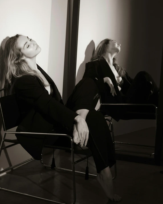 a woman sitting in a chair in front of a mirror, a black and white photo, by Emma Andijewska, happening, wearing causal black suits, britt marling style, having a good time, queer woman