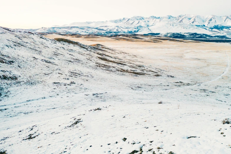 a man riding a snowboard down a snow covered slope, an album cover, by Hallsteinn Sigurðsson, trending on unsplash, land art, barren desert landscape, an expansive grassy plain, drone photo, (3 are winter