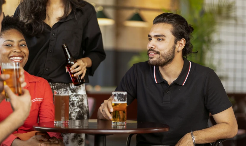 a group of people sitting around a table with drinks, profile image, light stubble with red shirt, aboriginal australian hipster, with a beard and a black shirt