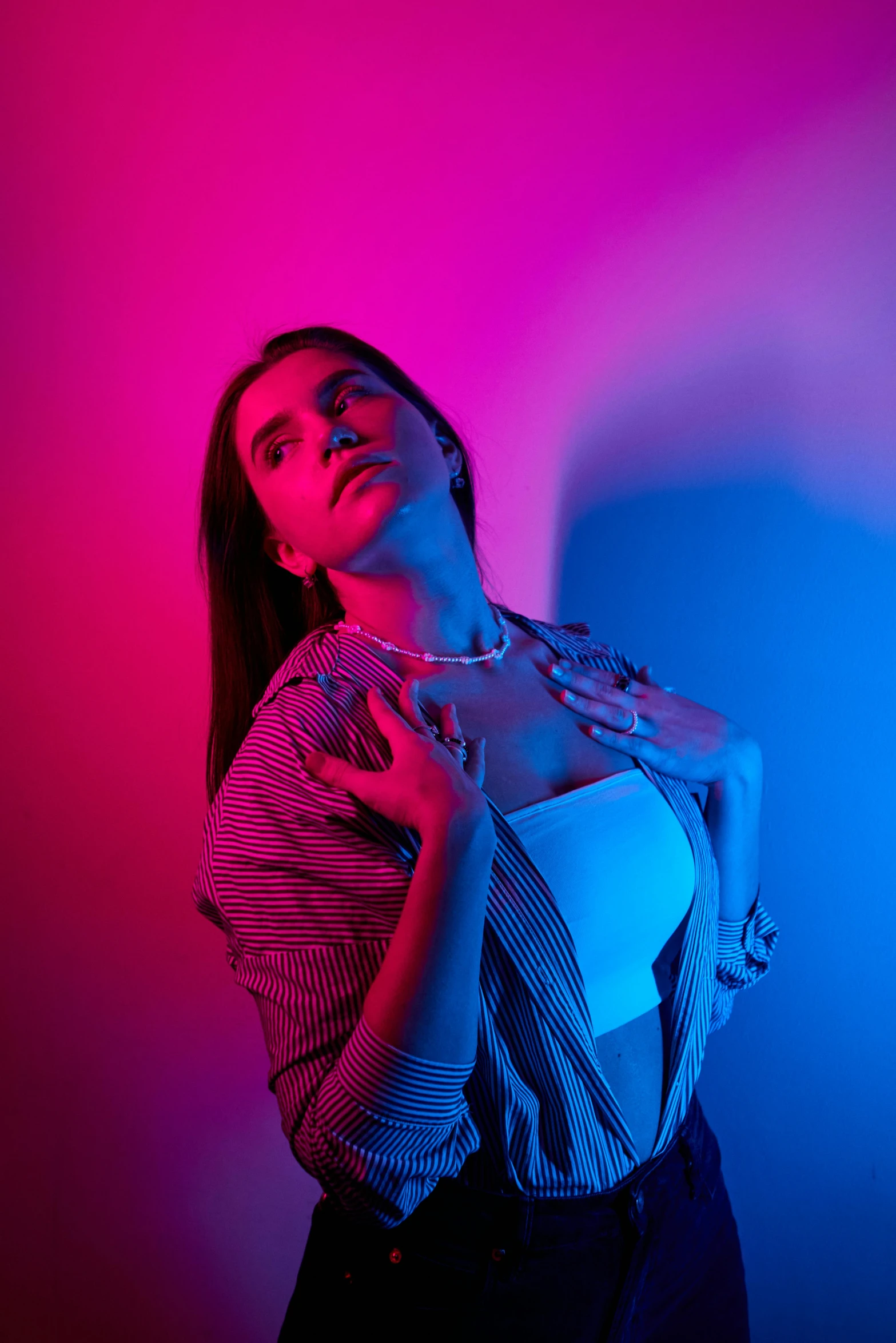 a woman standing in front of a pink and blue background, an album cover, inspired by Elsa Bleda, unsplash, blue and red lights, model shoot, 5 0 0 px models, bisexual lighting