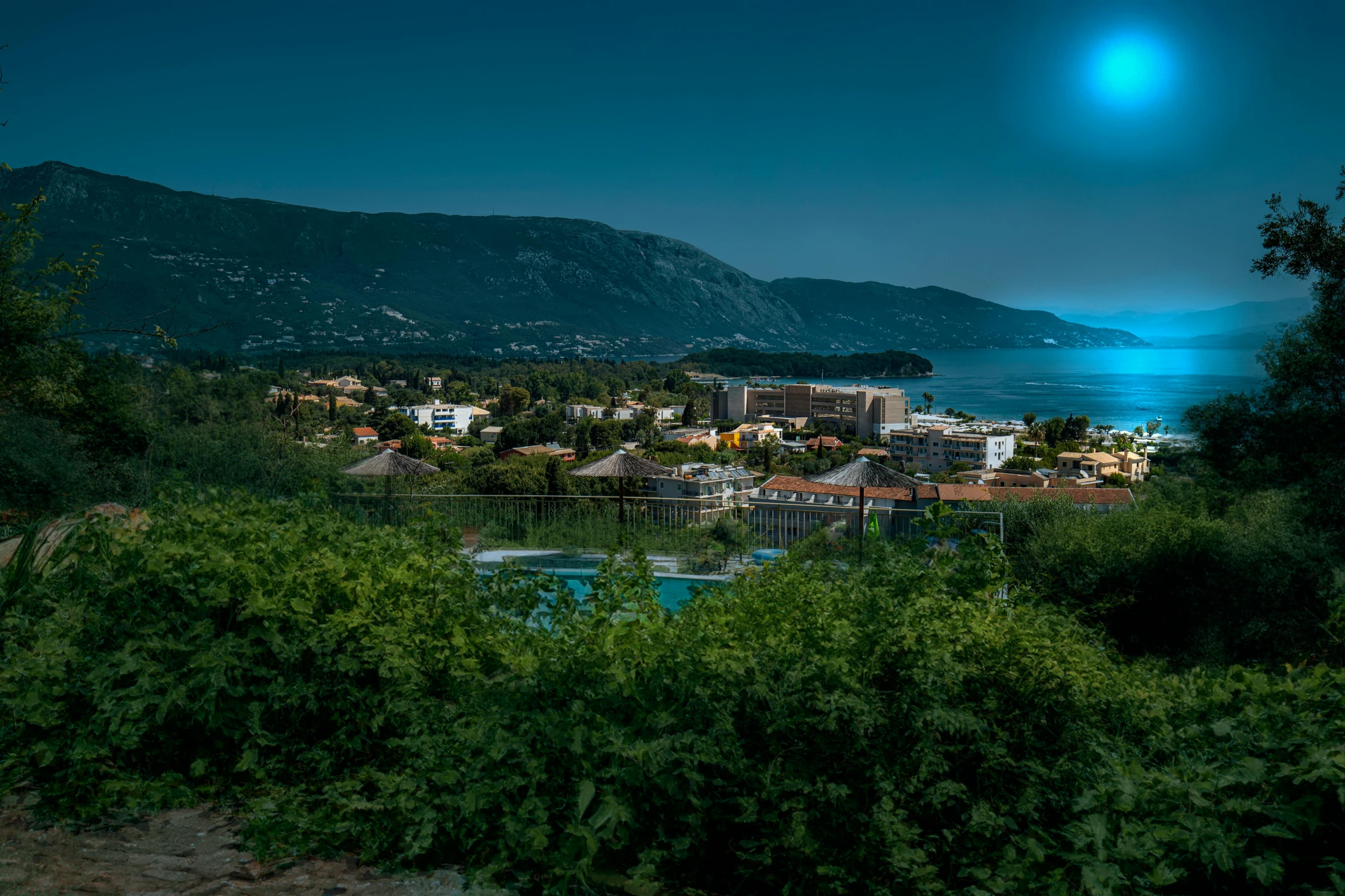 a large body of water next to a lush green hillside, by Alexis Grimou, pexels contest winner, under a full moon, mediterranean fisher village, 4 k cinematic panoramic view, blue