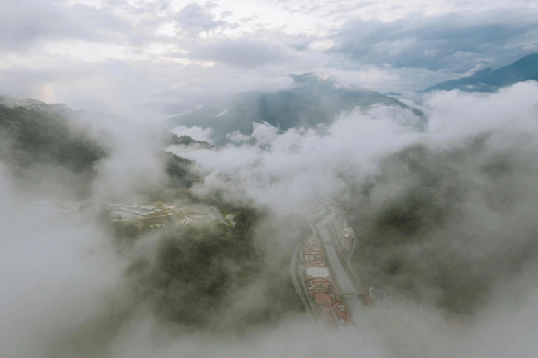 a train traveling down a train track surrounded by clouds, pexels contest winner, hurufiyya, helicopter view, mountain fortress city, dense volumetric fog, drone photograpghy