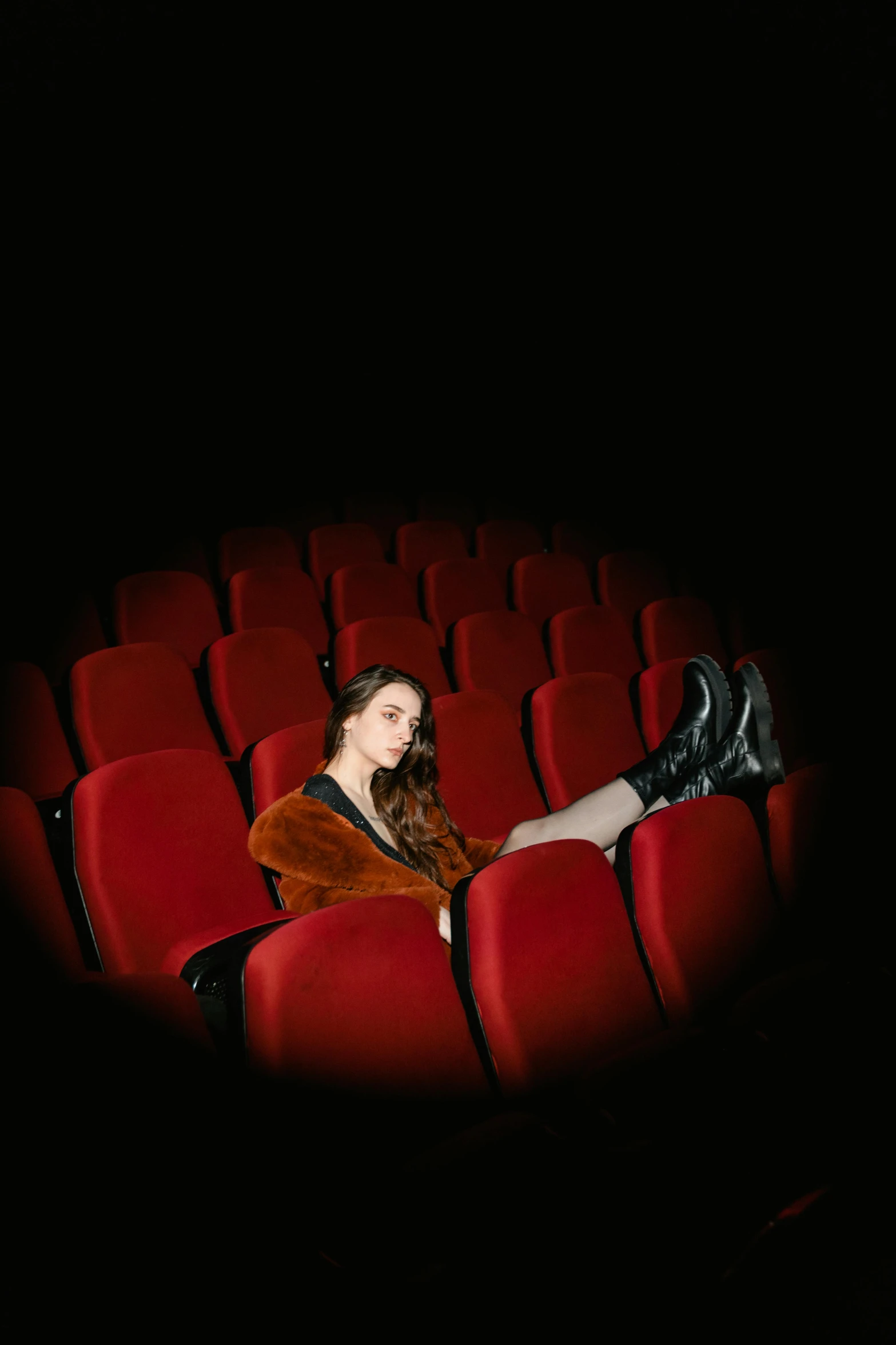 a woman sitting in the middle of a movie theater, antipodeans, wearing boots, portrait sophie mudd, [ theatrical ], single