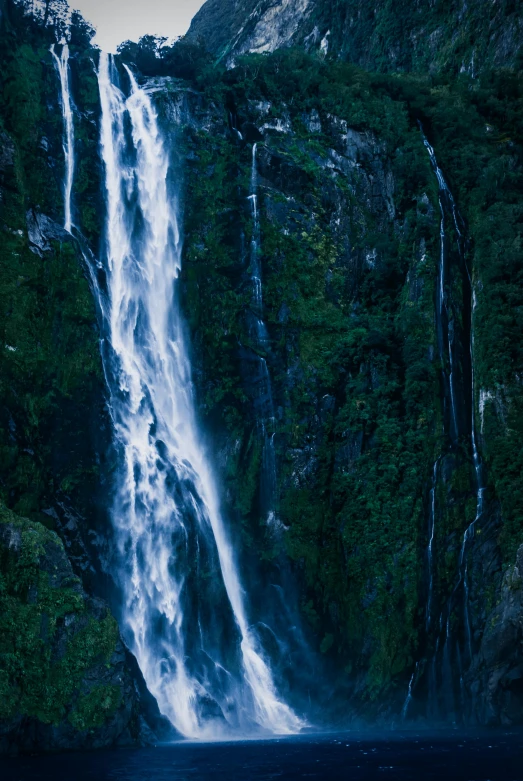 a large waterfall in the middle of a lush green forest, by Peter Churcher, taken at golden hour, null, blue, te pae