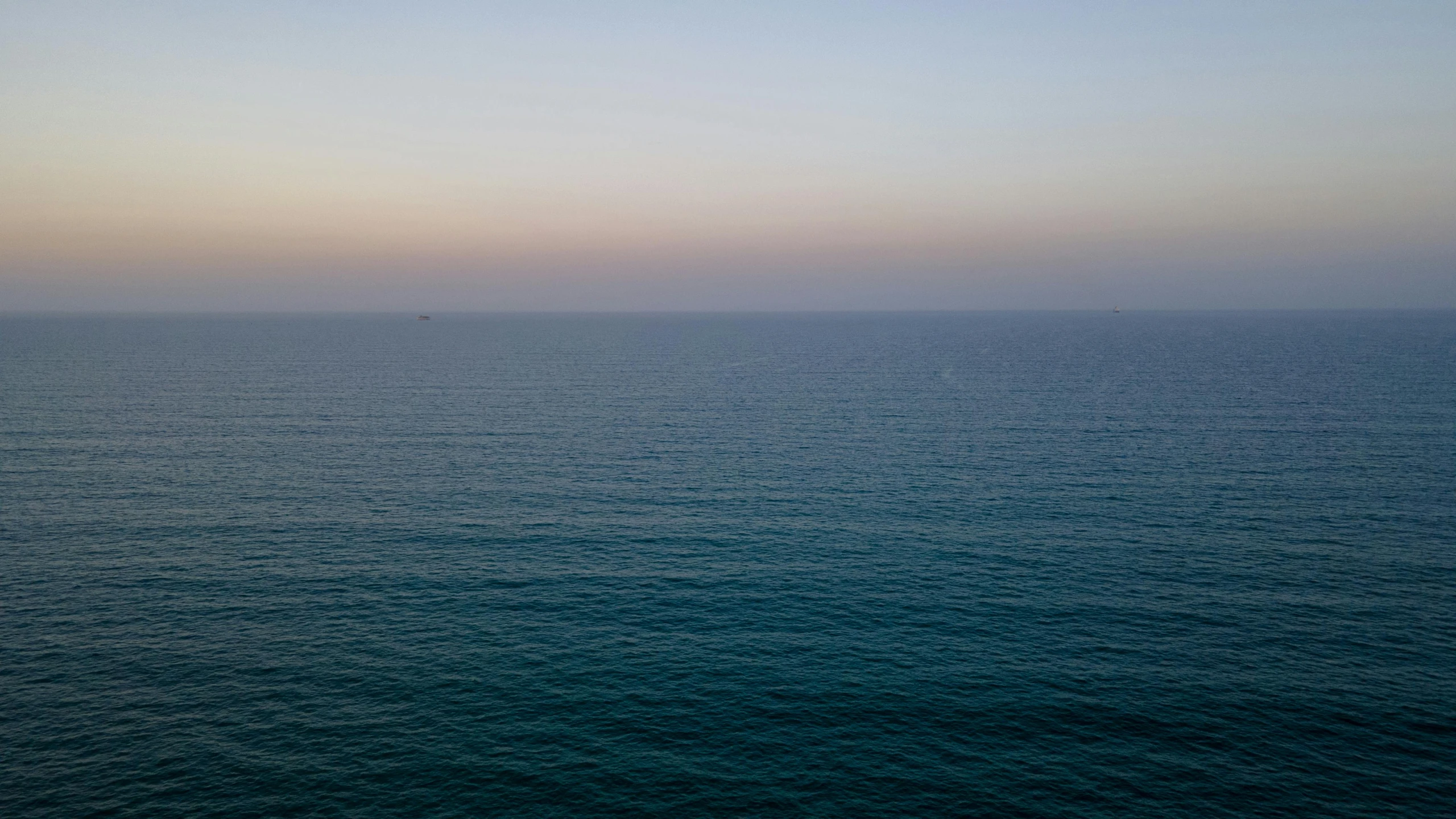 a large body of water with a boat in the distance, an album cover, inspired by Elsa Bleda, unsplash, minimalism, nadav kander, fades to the horizon, mediterranean, early evening