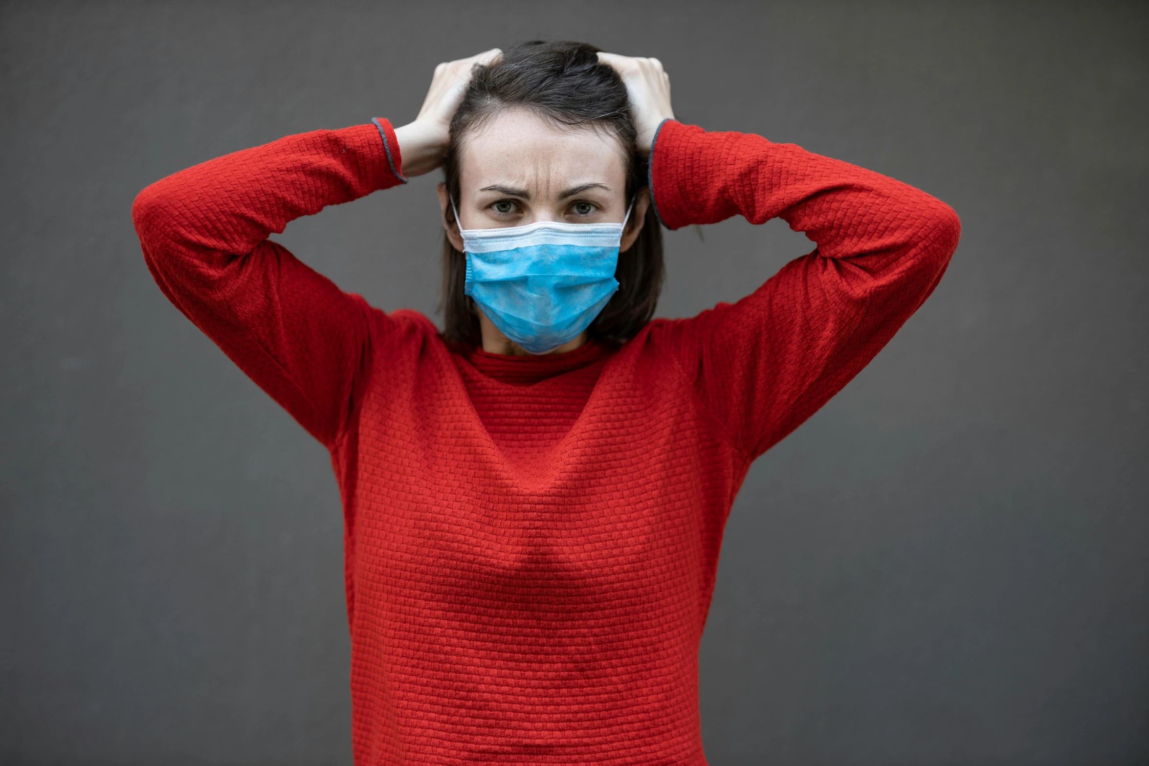 a woman with a medical mask covering her face, a portrait, by Adam Marczyński, shutterstock, hurufiyya, red sweater and gray pants, frustrated face, square, on a gray background