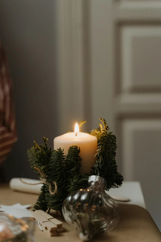 a lit candle sitting on top of a table, organic ornament, holiday vibe, glowing with silver light, pine