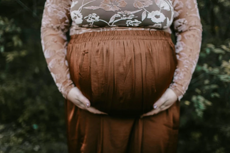 a pregnant woman standing in front of a forest, trending on pexels, happening, brown pants, bbw, ornately dressed, an anthropomorphic stomach