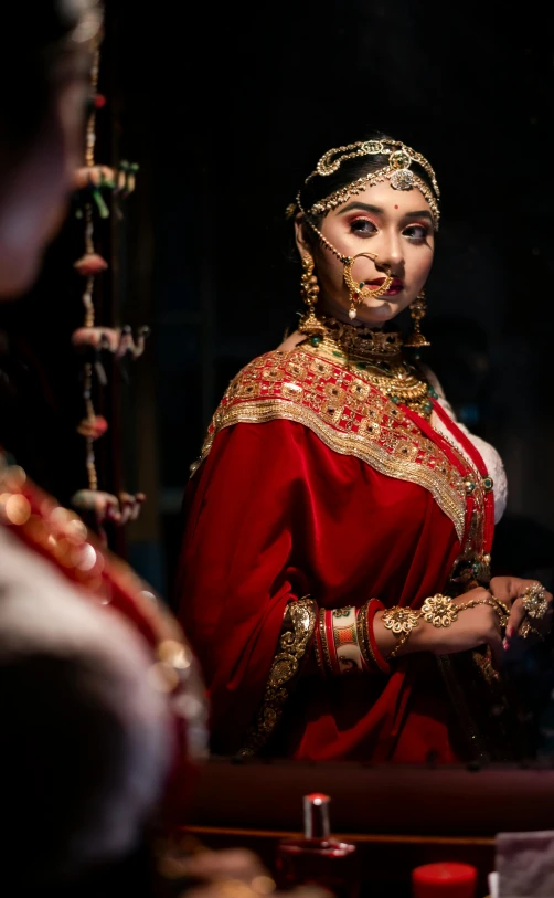 a woman in a red dress standing in front of a mirror, inspired by Osman Hamdi Bey, pexels contest winner, bride, elaborate costume, wearing gold jewellery, movie promotional image