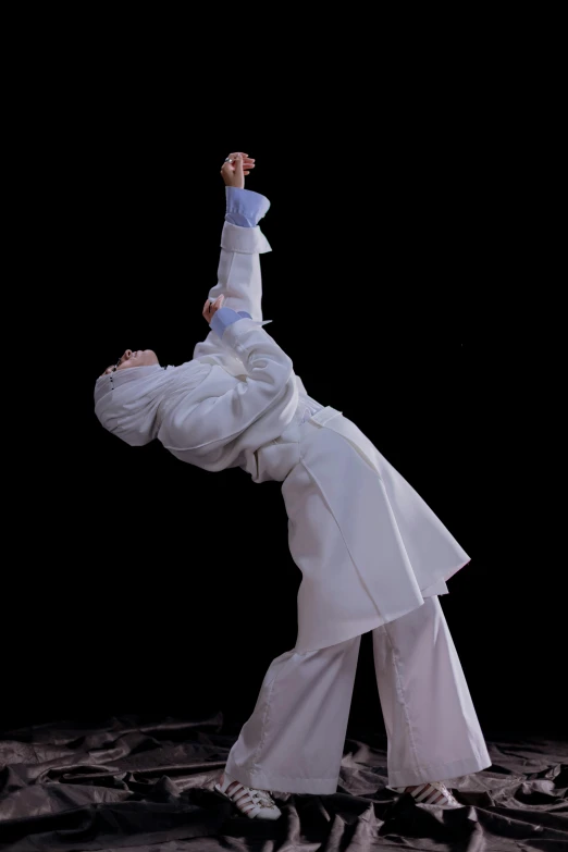 a man doing a handstand in front of a black background, an album cover, inspired by Liao Chi-chun, arabesque, wearing white robes, white hijab, wearing a track suit, 15081959 21121991 01012000 4k