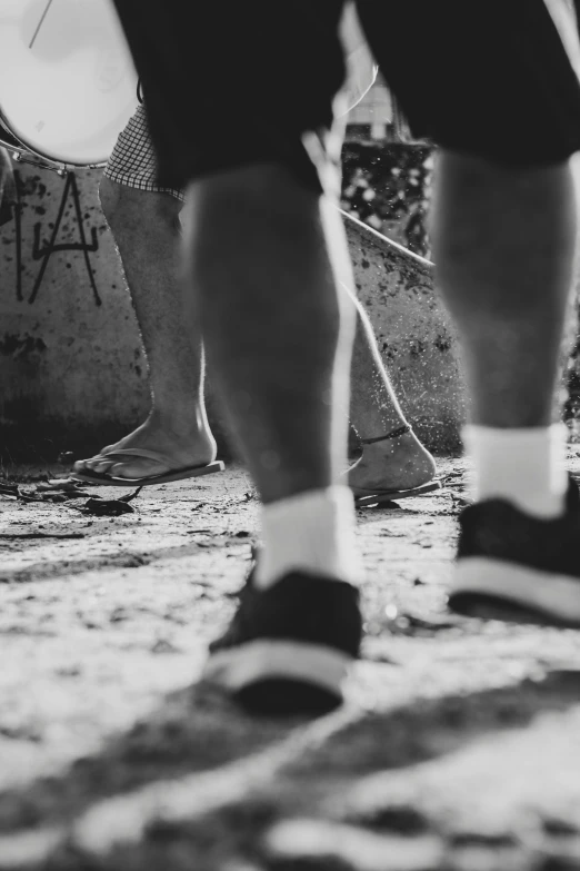 a black and white photo of a person with a skateboard, a black and white photo, by Lucia Peka, unsplash, realism, gray shorts and black socks, walking together, big feet, criminals