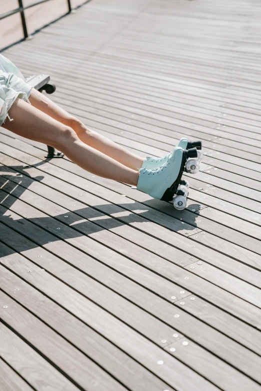 a woman riding a skateboard on top of a wooden floor, a colorized photo, trending on unsplash, seafoam green, knobbly knees, pale blue, laying down