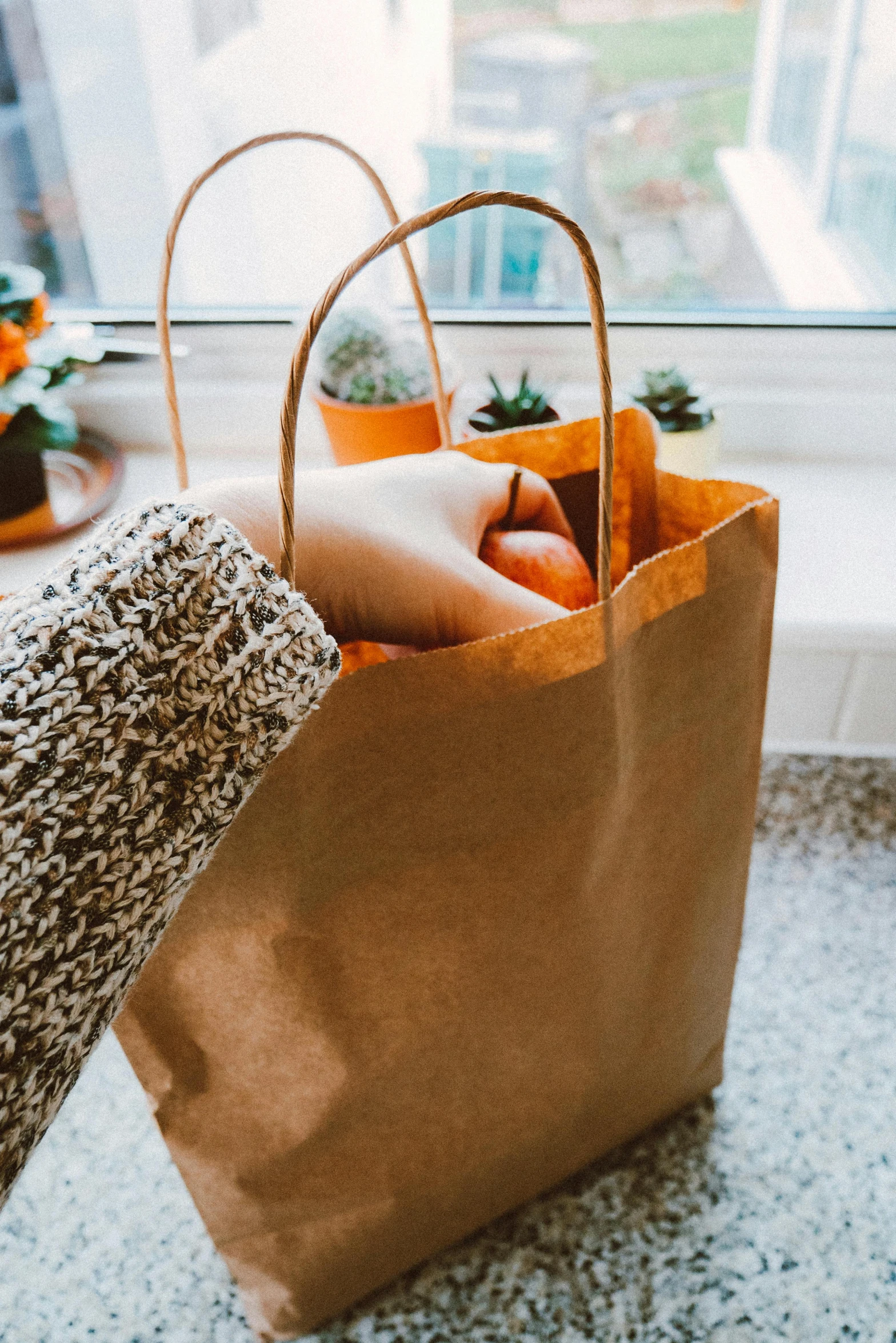 a person holding a brown paper bag filled with vegetables, orange hue, at home, square, stores