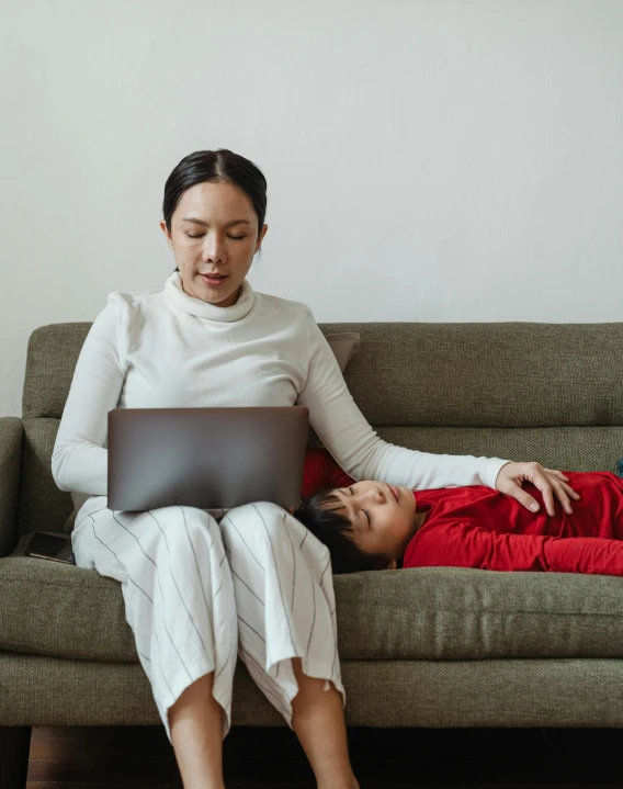 a woman sitting on a couch with a child on her lap, a cartoon, pexels contest winner, incoherents, typing on laptop, asian male, sleepy, non binary model