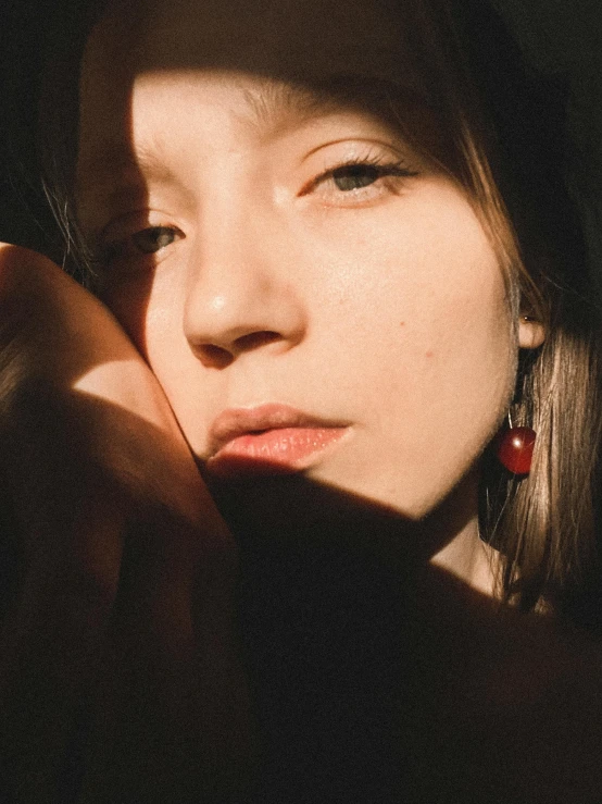 a close up of a person holding a cell phone, inspired by Elsa Bleda, photorealism, earrings, soft shadows on the face, red filter, instagram story