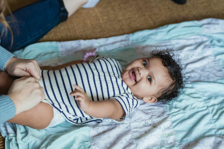 a baby laying on top of a blanket next to a woman, pexels contest winner, happening, a confident smile, bowater charlie and brom gerald, an olive skinned, full length shot