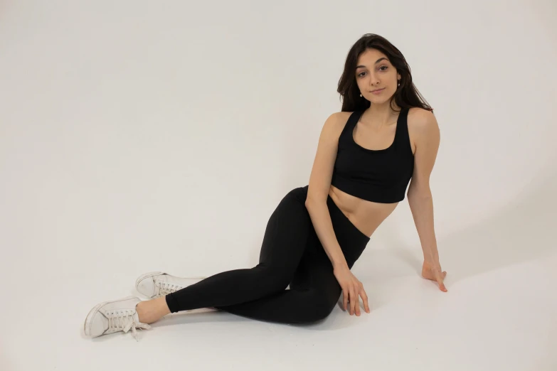 a woman sitting on the ground in a black top and leggings, inspired by Ion Andreescu, wearing a cropped black tank top, natural tpose, seamless, persian princess