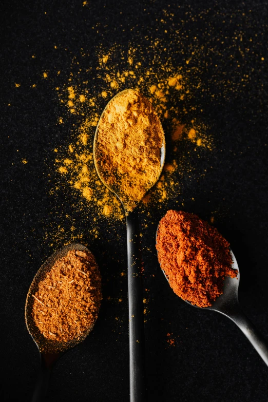 three spoons filled with different types of spices, a digital rendering, by Adam Marczyński, trending on pexels, color palette is dark orange, iron, a high angle shot, yellow ochre