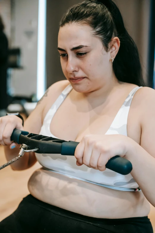 a woman in a white tank top is using a pair of scissors, a colorized photo, inspired by Ion Andreescu, pexels contest winner, holding a crowbar, thicc, dingy gym, ameera al-taweel