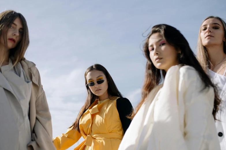 a group of women standing next to each other, trending on pexels, aestheticism, yellow clothes, asian descent, bella poarch, blue sky