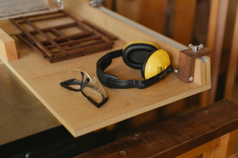 a pair of headphones sitting on top of a table, arbeitsrat für kunst, yellow carrera glasses, workbench, wooden casing, detailed product image