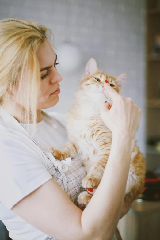 a woman holding a cat in her arms, pexels, a blond, smelling good, orange fluffy belly, kitch