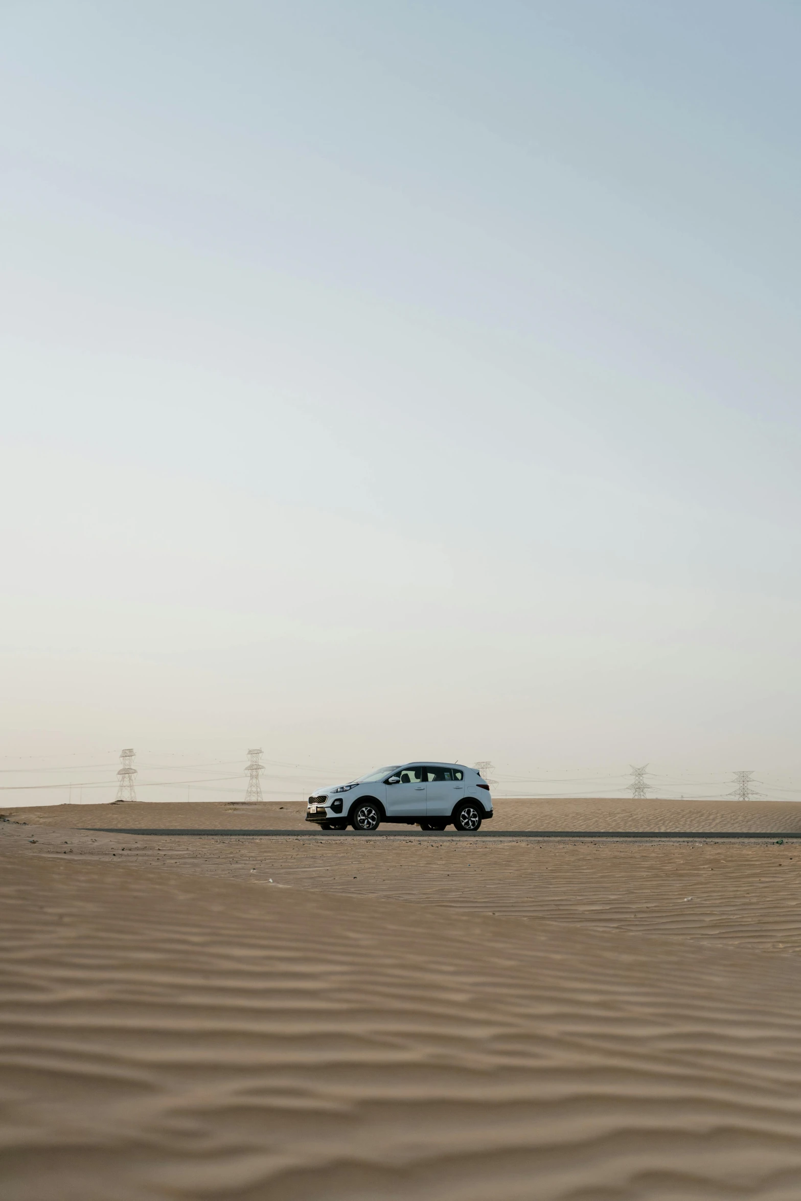 a car that is sitting in the sand, a picture, unsplash, in the desert beside the gulf, square, high resolution photo, medium long shot