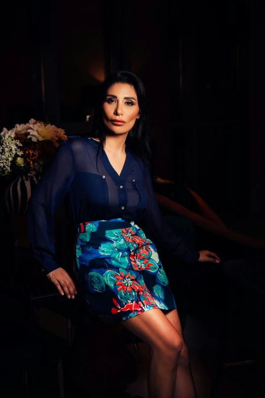 a woman sitting on a chair in a dark room, a portrait, instagram, hurufiyya, lady with glowing flowers dress, sarah shahi, official store photo, 15081959 21121991 01012000 4k