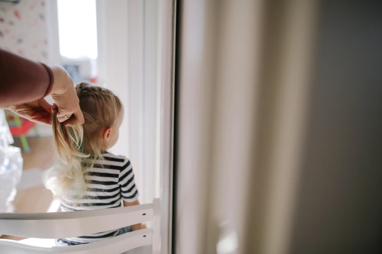 a little girl that is sitting in a chair, by Emma Andijewska, pexels contest winner, hair detailing, striped, a blond, window