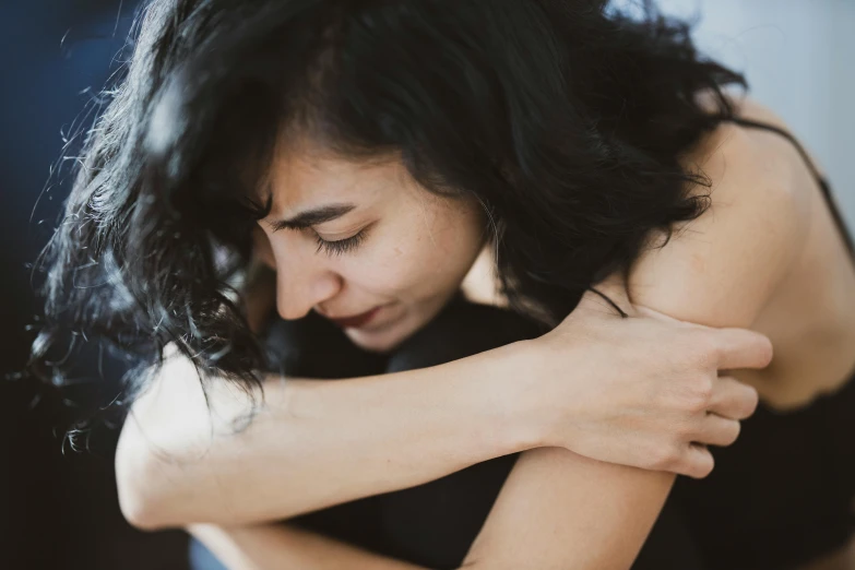 a beautiful young woman sitting on top of a bed, trending on pexels, hurufiyya, hugging each other, grieving. intricate, looking her shoulder, slightly blurred