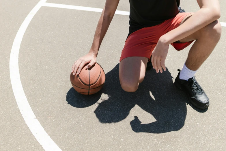 a man kneeling on a basketball court holding a basketball, trending on dribble, 15081959 21121991 01012000 4k, perfect shadow, guide, wearing red shorts