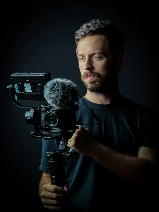 a man holding a video camera on a tripod, a portrait, by Adam Szentpétery, unsplash contest winner, video art, on black background, halfbody headshot, irish youtuber, product introduction photo